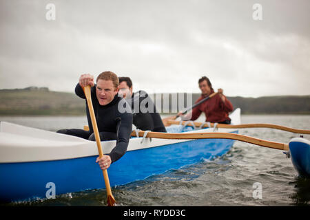 Drei junge Erwachsene zusammen Paddeln in einem Kanu auf dem See. Stockfoto