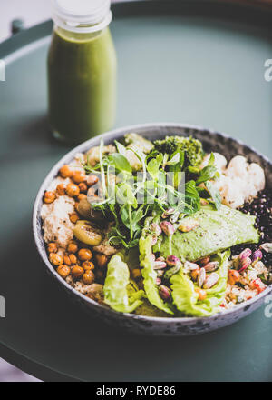 Gesundes Mittag- oder Abendessen zu Hause. Vegan superbowl oder Buddha Schüssel mit Hummus, Gemüse, frischen Salat, Bohnen, Couscous und Avocado und grünen Smoothie in Stockfoto