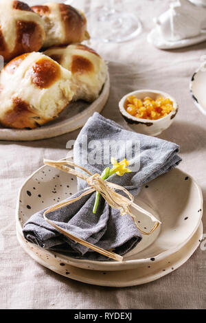Ostern Tisch mit Teller von Hot Cross Buns auf Tabelle mit Bettwäsche Tischdecke. Nahaufnahme Stockfoto
