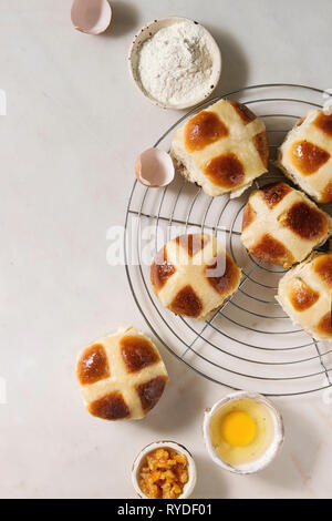 Hausgemachte Ostern traditionelle Hot Cross Buns auf Kühlung Rack mit Zutaten oben auf weißem Hintergrund. Ansicht von oben, Raum Stockfoto