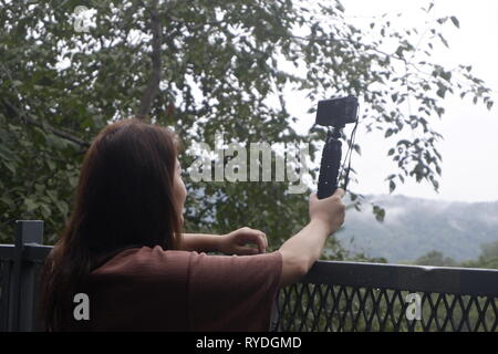 Junge weibliche Reisende unter Bild der Wald-, Berg mit der Kamera anzeigen. Stockfoto