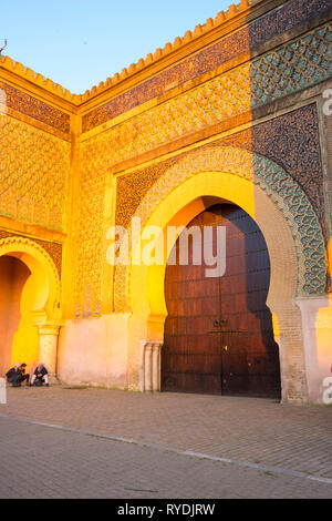 Meknes, Marokko - April 4, 2018: Marokkaner vor der Bab El-Mansour historischen Tor während der Goldenen Stunde zu spät am Nachmittag. Vertikale Stockfoto