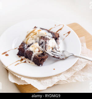 Chocolate Brownie mit einer Kugel Vanilleeis mod Schokoladensauce auf einer weißen Platte Stockfoto
