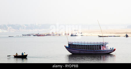 Schönes Boot in der Mitte der Winter Fluss Ganges, Boote für den Transport von Menschen über den Fluss und viele Pilger baden in der heiligen Fluss auf Sandbank Stockfoto