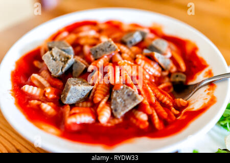 Nahaufnahme der Schüssel mit Wurst Stücke und pasta Gnocchi sardi Sardische Form mit roten Tomatensauce marinara Sauce mit Gabel oder Löffel Stockfoto