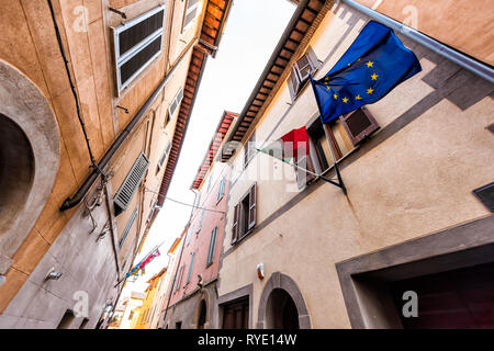 Chiusi, Italien Straße in kleinen mittelalterlichen Stadt Dorf in der Toskana suchen, Low Angle View mit bunten Wänden und europäischen Flaggen Stockfoto