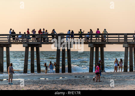 Neapel, USA - 29. April 2018: Florida gelber Sonnenuntergang im Golf von Mexiko mit Pier Holzsteg und Masse von vielen Menschen auf dem berühmten beliebten Säulen in h Stockfoto