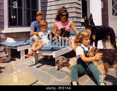 Kennedy Familie mit Hunden während einem Wochenende in Hyannisport - Hyannisport Wochenende. Präsident Kennedy, John F. Kennedy jr., Frau Kennedy, Caroline Kennedy. Hunde: Clipper (stehend), Charlie (mit Caroline), Wolf (liegend), Shannon (mit John jr.), zwei von Pushinka's Welpen (mit Frau Kennedy). August 1963 Stockfoto