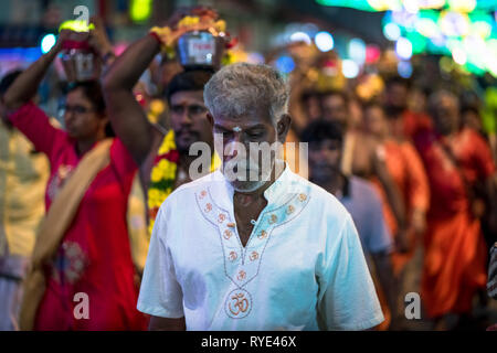 Schöne ältere Mann im weißen Hemd, führenden die Devotees balancing Milch Töpfe - Thaipusam Festival - Singapur Stockfoto