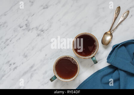 Morgen Komposition mit zwei Tassen schwarzen Kaffee und blau serviette sind auf einem Marmor Oberfläche mit Platz für Text, Ansicht von oben Stockfoto