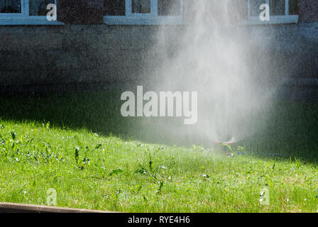 Automatisches Drehen der Sprinkleranlage die Bewässerung des Rasens auf dem Hintergrund des grünen Grases, close-up Stockfoto