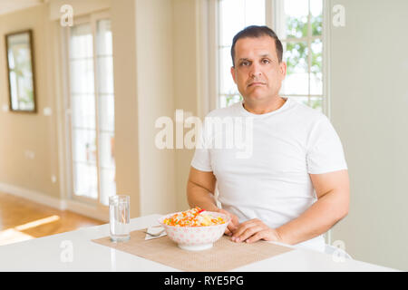 Mittleres Alter Mann Reis zu Hause essen mit ernsten Gesichtsausdruck. Einfache und natürliche in die Kamera schaut. Stockfoto