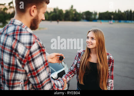 Fahrlehrer Schlüssel gibt an weibliche Fahrer Stockfoto