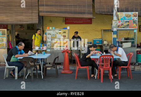 Die Menschen essen und trinken Tee und Kaffee an den Imbissständen in den Straßen von Georgetown, Penang, Malaysia, Asien Stockfoto