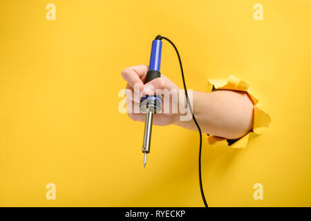 Hand mit einem Lötkolben Stockfoto