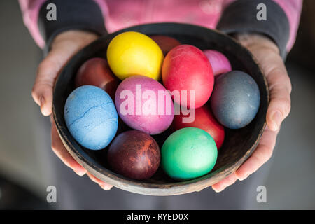 Bunte Ostereier in Schüssel in der Frau die Hände. Stockfoto