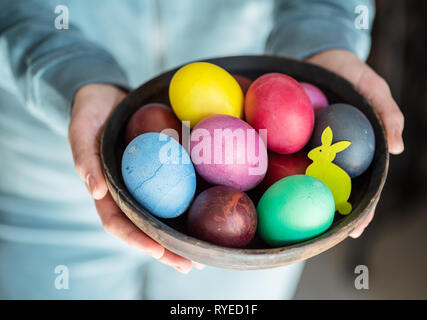 Bunte Ostereier in Schüssel in der Frau die Hände. Stockfoto