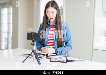 Schöne asiatische Einflussnehmer Frau Aufnahme Make-up Tutorial über Smartphone-kamera Angst und mit Erstaunen Ausdruck, Angst und aufgeregt Gesicht schockiert Stockfoto