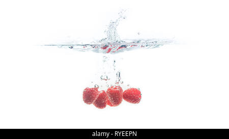 Bündel von saftig lecker aussehenden Himbeeren Spritzer in die Wasseroberfläche und Untergang. Auf weißem Hintergrund, Splash essen Fotografie. Stockfoto