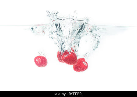 Bündel von saftig lecker aussehenden Himbeeren Spritzer in die Wasseroberfläche und Untergang. Auf weißem Hintergrund, Splash essen Fotografie. Stockfoto