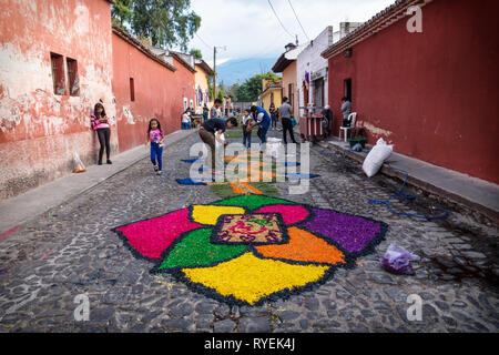 Antigua, Guatemala - 23. März 2018: Die einheimischen Kinder schaffen Alfombre bunte Blume Teppiche auf den gepflasterten Straßen Stockfoto