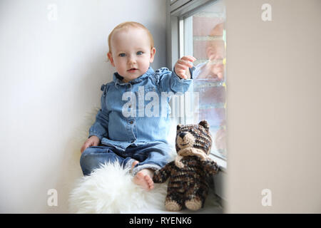 Hübsches Kind sitzt am Fenster Kühlen Stockfoto