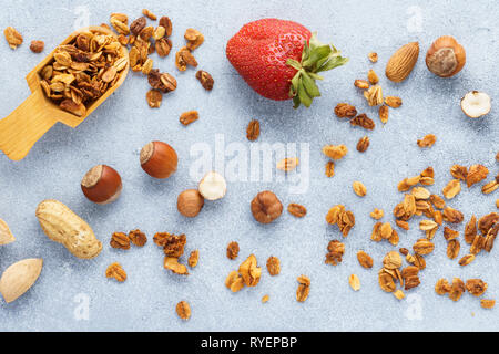 Gesundes Müsli, Erdbeeren und Zutaten - Hafer und verschiedene Nüsse. Stockfoto