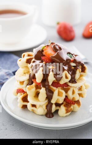 Belgische Waffeln mit Erdbeeren, Banane und fließende Schokolade zum Nachtisch. Stockfoto