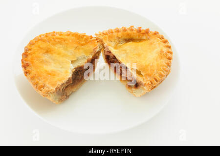 Herzhafte Fleisch takeaway Kuchen mit einer Füllung in der Hälfte auf einer weißen Platte Stockfoto