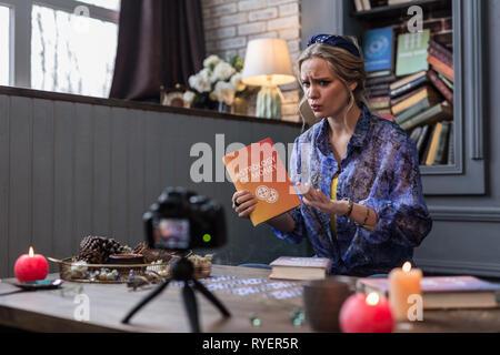 Angenehme junge Frau spricht über ein interessantes Buch Stockfoto