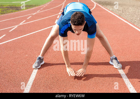 Marathon Vorbereitung. Junger Mann auf Stadion draußen Bücken stretching konzentriert Stockfoto