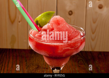 Sorbet Eis Erdbeer Geschmack mit zwei strohhalme und Zitronenscheibe in eine Glasschüssel auf hölzernen Tisch serviert Stockfoto