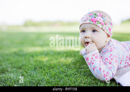 Cute Baby Mädchen liegen auf Gras im Sommer Park und Suchen Stockfoto