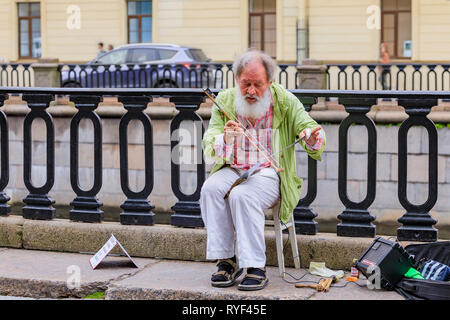Sankt Petersburg, Russland - 10. September 2017: Alter mann Street Performer mit Bart, in schäbigen Kleidung spielen eine Hand sah für Geld auf dem Stockfoto