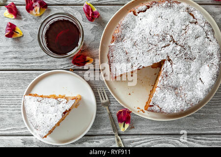 Hausgemachte vegan Apfelkuchen Charlotte, serviert mit einem Glas Tee auf einem Holztisch. Ansicht von oben, flach Stockfoto