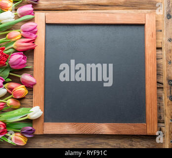 Bunte Tulpen so angeordnet, wie sie Rahmen auf Holz- Hintergrund. Ansicht von oben. Stockfoto