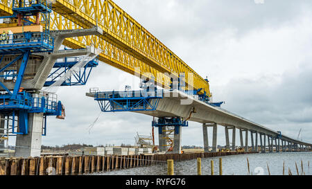 Granitblock verkleben Elemente aus Beton auf der Baustelle einer neuen Brücke über den Roskilde Firth, mit einem riesigen gelben Kran. Frederikssund, D Stockfoto