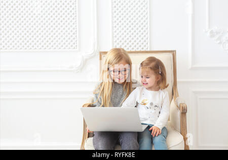 Zwei adorable lächelnd litle Schwestern gemeinsam mit Ihrem Computer Laptop Stockfoto