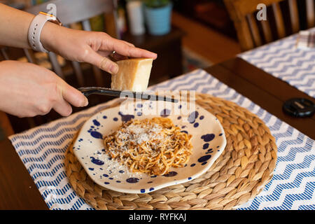 Frau Hände reiben Parmesan hausgemachte Spaghetti Bolognese, traditionelle Pasta mit Fleisch und Gemüse Stockfoto