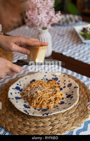 Frau Hände reiben Parmesan hausgemachte Spaghetti Bolognese, traditionelle Pasta mit Fleisch und Gemüse Stockfoto