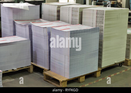 Stapel gedruckter Blätter aus Pappe auf Holzpaletten closeup. Druckindustrie Stockfoto