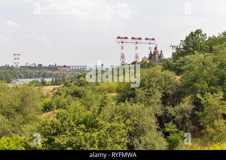 Mittelalterliche hölzerne Kirche, Tempel der Kosaken. Gebäude auf Zaporozhskaya sich und Hochspannungsleitungen Türme auf der Insel Khortytsia in der Ukraine. Stockfoto