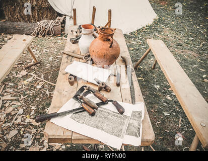 Alte Holzbearbeitung Werkzeug Hand, drawknife drawshave, Zeichnung Messer, Rasieren knifewooden in einer Schreinerei auf schmutzigen rustikalen Tisch mit alten Ton Stockfoto