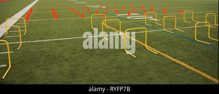 Orange Kegel und gelb Hürden sind auf dem grünen Rasen Feld für den Praxis für High School Sport gesetzt. Stockfoto