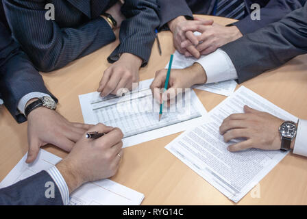 Gruppe von Geschäftsleuten kräftig diskutieren, Pläne und Strategien des Unternehmens und Verträge an einem Tisch sitzen in einem Schließen Schließen-Unternehmen Stockfoto