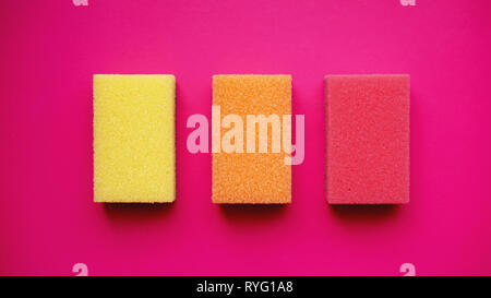 Schwämme - Ansicht von oben. Haushalt Reinigung Konzept. Bunte orange rosa gelb Schwämme auf rosa Hintergrund. Stockfoto