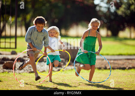 Gerne Geschwister spielen mit Hula Hoops in Ihrem Hinterhof. Stockfoto