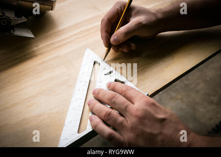 Des Menschen Hände Kennzeichnung Messung auf Sperrholzplatte mit einem Bleistift und Geschwindigkeit. Stockfoto