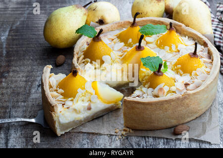 Köstliche Kuchen mit pochierten Birnen und Mandelflocken auf hölzernen Tisch Stockfoto