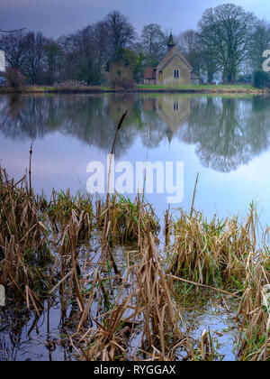 Sonnenaufgang über St Leonard's Kirche und Hartley Mauditt Teich, in der Nähe von Alton, in der South Downs National Park, Hampshire, Großbritannien Stockfoto